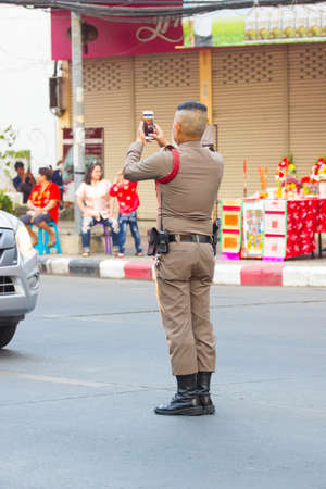 NAKHON SAWAN, THAILAND - FEBRUARY 8 : unidentified asian policeman taking photos at dragon parade in Chinese New Year festival on February 8, 2019 in  Nakhon Sawan, Thailand.のeditorial素材