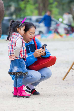 CHIANG RAI, THAILAND - JANUARY 13 : Unidentified mother showing photos in a mobile phone to her daughter on January 13, 2018 in Chiang rai, Thailand.のeditorial素材