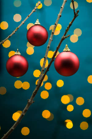 Red Christmas decoration in front of lights on tree branchの写真素材