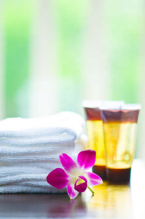 Spa towels and orchid flower in front of a white green backgroundの写真素材