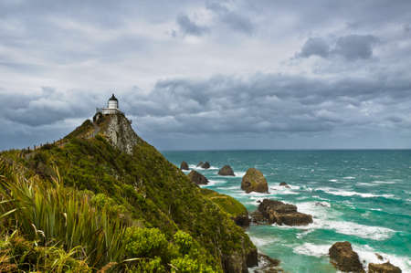Nugget Point Light House an dark clouds in the sky, Catlins, New Zealandの写真素材