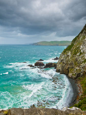 Cliffs under thunder clouds right before a storm and turquoise oceanの写真素材