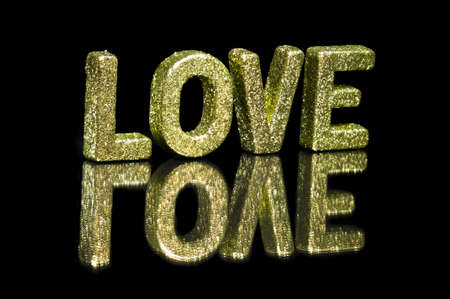 In capital letter written love, glitter effect over blackの写真素材