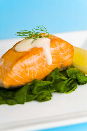 Salmon steak on spinach, decorated with lemon, sauce and dillの写真素材
