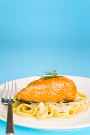 Salmon steak on pasta, decorated with dill and forkの写真素材