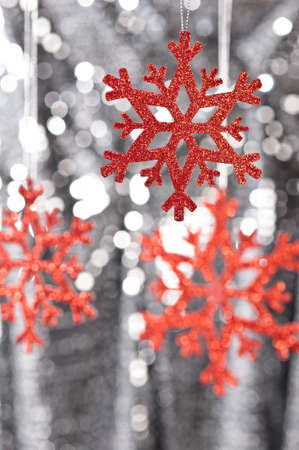 Red snow flake on a silver glitter background for Christmasの写真素材