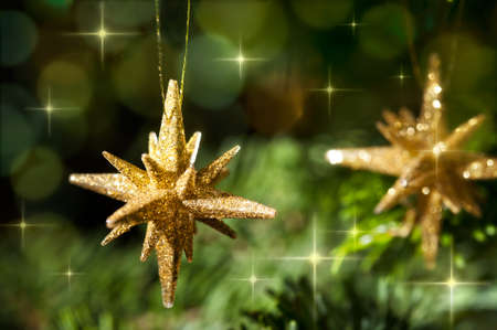 Decorative Gold Star ornament in a Christmas tree infront of a glitter backgroundの写真素材