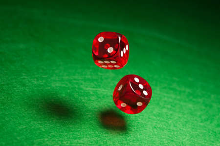 Rolling red dice over green surfaceの写真素材