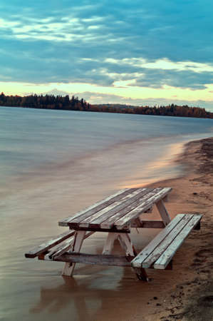 Bench and table sunk into the sand on a beachの写真素材