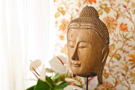Buddha head in front of floral wallpaper