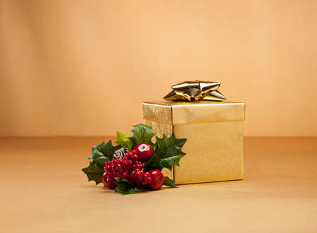 Gold present and holly isolated over goldの写真素材