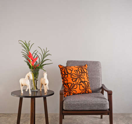 
Grey upholstered chair with flower and orange pillow の写真素材