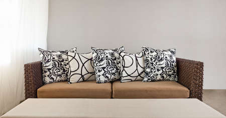 Beige sofa with colourful pillows in simple settingの写真素材