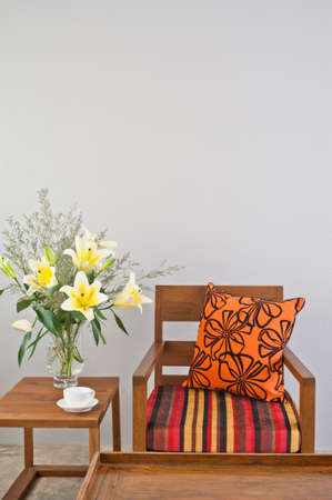 Colorful upholstered chair with side table and flowersの写真素材