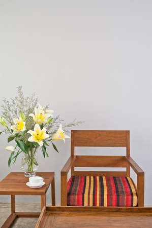 Colorful upholstered chair with side table and flowersの写真素材