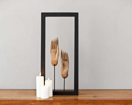 Buddhas hands framed with three lit candlesの写真素材