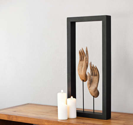 Buddhas hands and white candles on side boardの写真素材