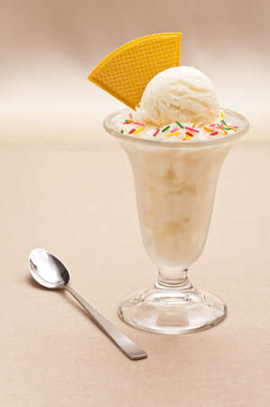 Vanilla ice cream cup with wafer over beige backgroundの写真素材