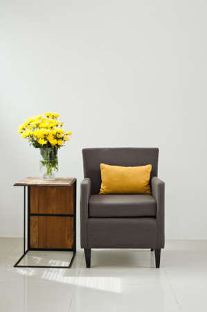Grey sofa armchair in simple setting with yellow flowersの写真素材
