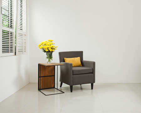 Grey sofa armchair in simple setting infront of lovered windowsの写真素材