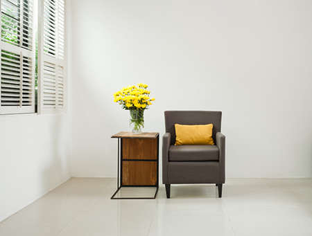 Grey sofa armchair in simple setting infront of lovered windowsの写真素材