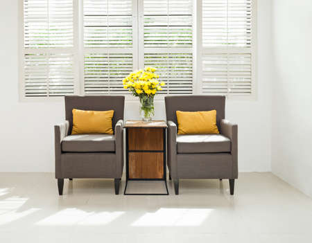 Grey sofa armchair in simple setting infront of lovered windowsの写真素材
