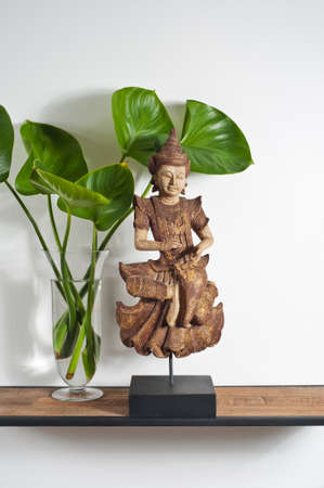 Buddha sculpture with green leafe decoration on side boardの写真素材