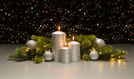 Three Silver Candles with Christmas tree branches decoratedの写真素材