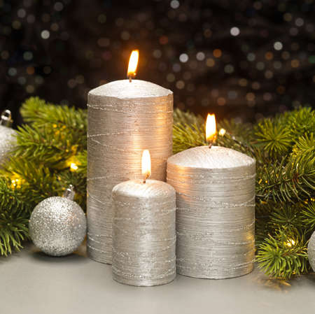 Three Silver Candles with Christmas tree branches decoratedの写真素材