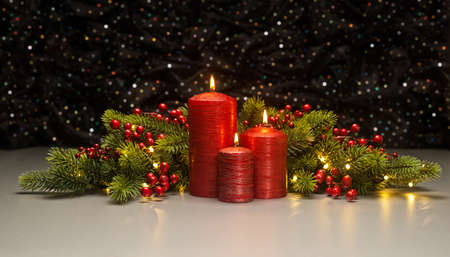 Three red Candles with Christmas tree branches and red berries decoratedの写真素材