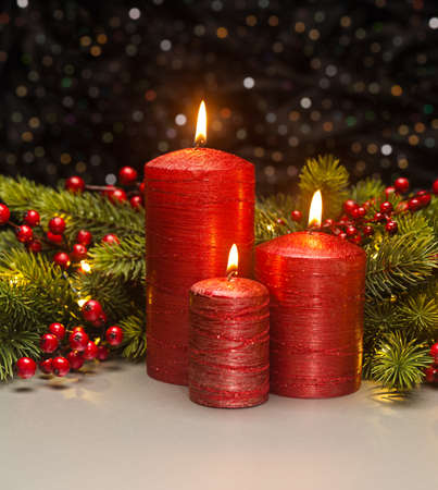 Three red Candles with Christmas tree branches and red berries decoratedの写真素材