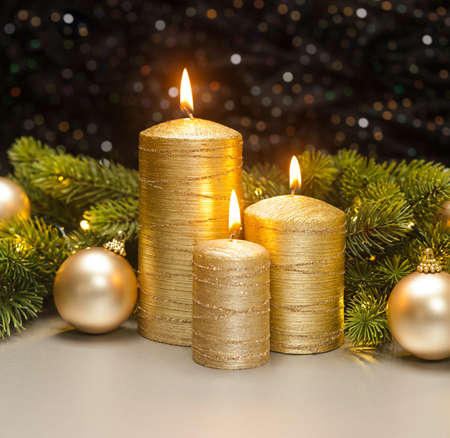 Three golden Candles with Christmas tree branches decoratedの写真素材