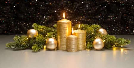 Three golden Candles with Christmas tree branches decoratedの写真素材