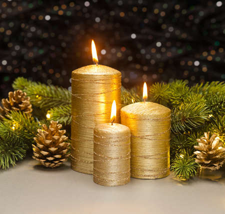 Three golden Candles with Christmas tree branches and pine cones decoratedの写真素材