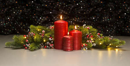 Three red Candles with Christmas tree branches and red berries decoratedの写真素材