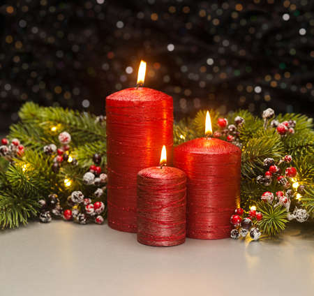 Three red Candles with Christmas tree branches and red berries decoratedの写真素材