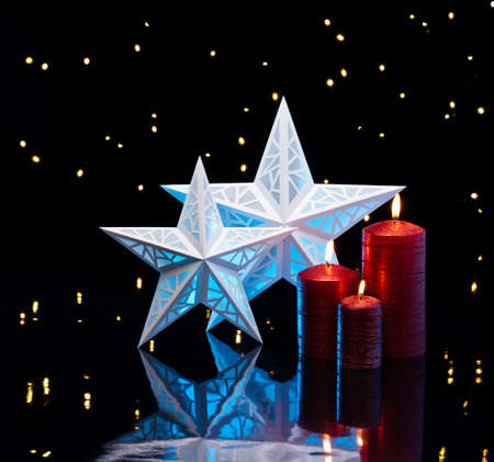 Backlit stars in blue with red candles in front of dark backgroundの写真素材