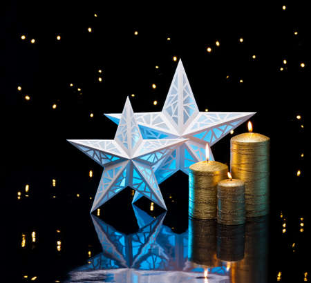 Backlit stars in blue with golden candles in front of dark background