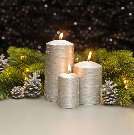 Three Silver Candles with Christmas tree branches and pine cones decoratedの写真素材