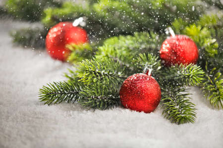Christmas tree bauble with snow falling and Christmas tree branchesの写真素材