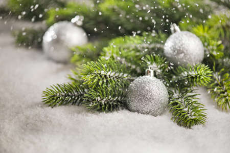Christmas tree bauble with snow falling and Christmas tree branchesの写真素材