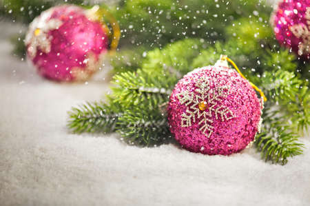 Christmas tree bauble with snow falling and Christmas tree branchesの写真素材