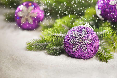 Christmas tree bauble with snow falling and Christmas tree branchesの写真素材