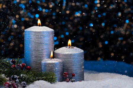 Three Silver Candles in snow with snowfallの写真素材