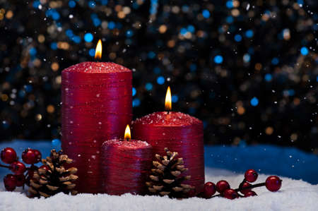 Three Red Candles in snow with snowfallの写真素材