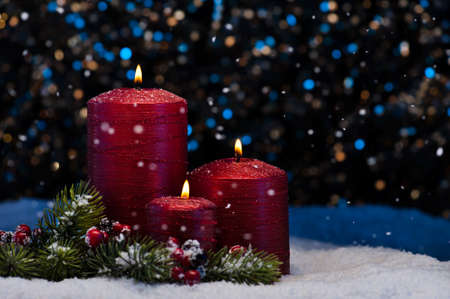 Three Red Candles in snow with snowfallの写真素材