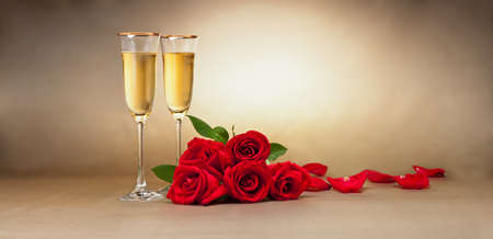 Champagne glasses, present and roses in front of beige backgroundの写真素材