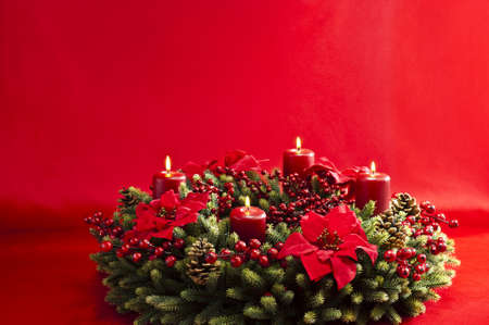 Advent wreath over red background with winter rose and berriesの写真素材
