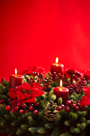 Advent wreath over red background with winter rose and berriesの写真素材
