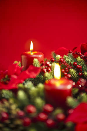 Advent wreath over red background with winter rose and berriesの写真素材